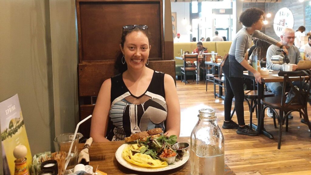 Sitting at a table at First Watch with an omelet, toast, and greens