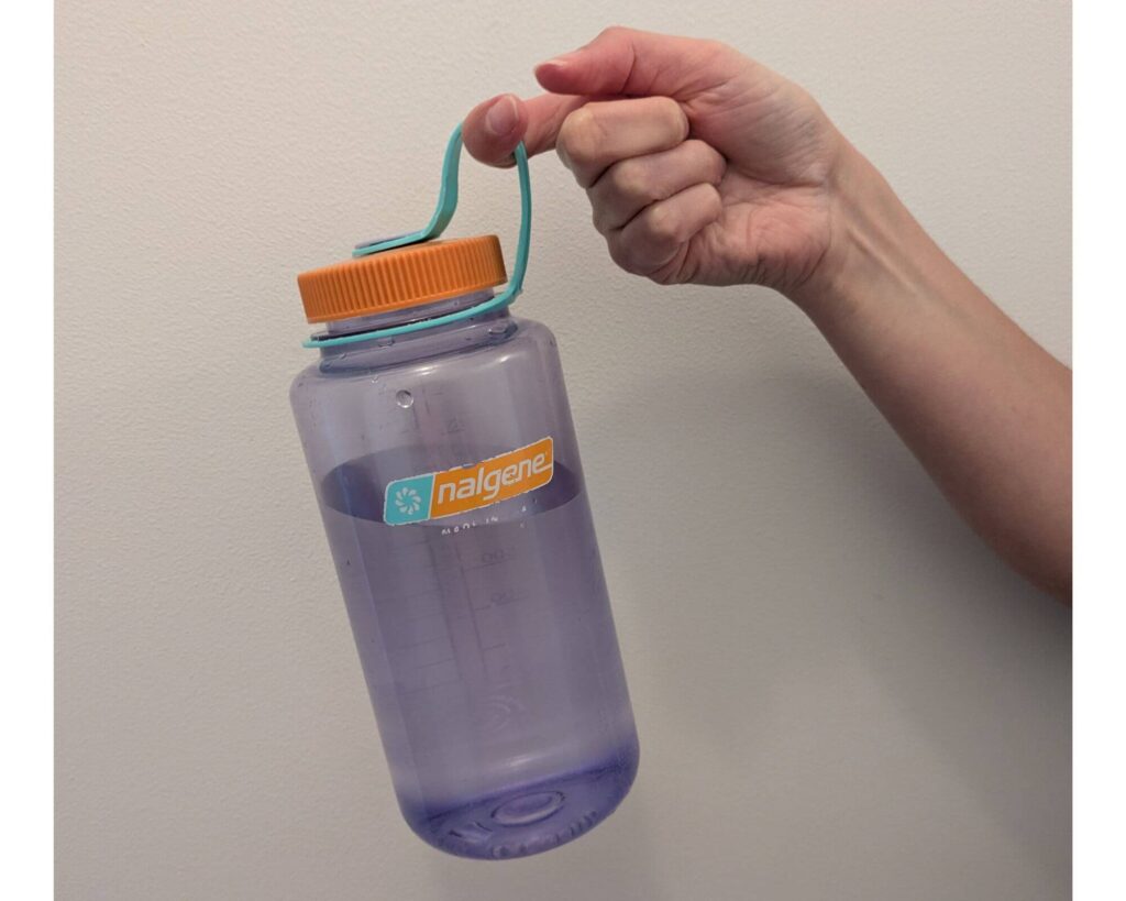 Holding a light purple with orange cap Nalgene bottle