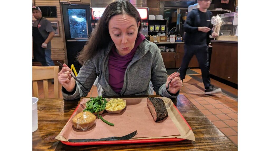 Diner looking at their tray of brisket, mac and cheese, green beans, and corn bread at Terry Black's