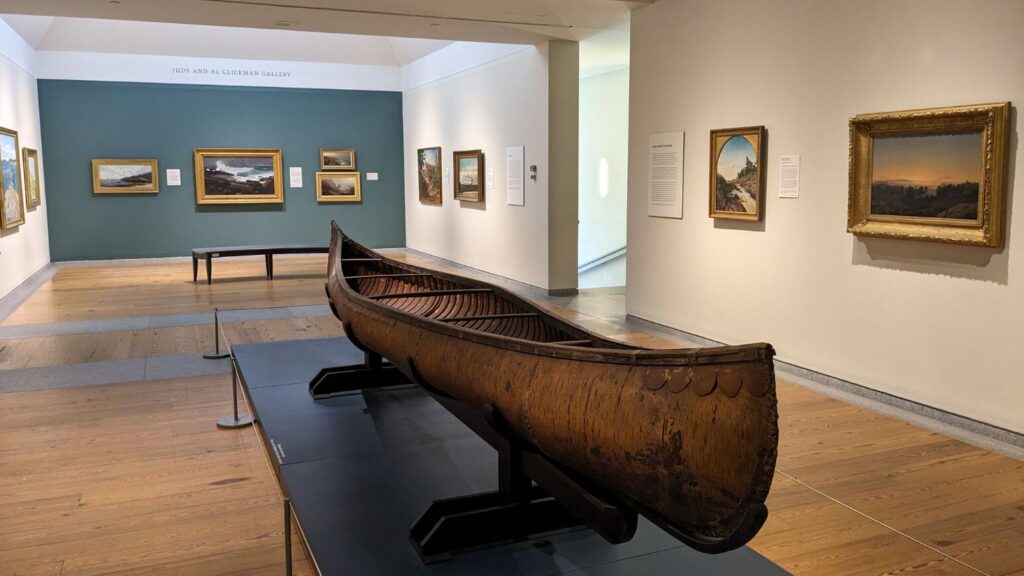 Canoe and paintings in the Passages in American Art exhibit at the Portland Museum of Art