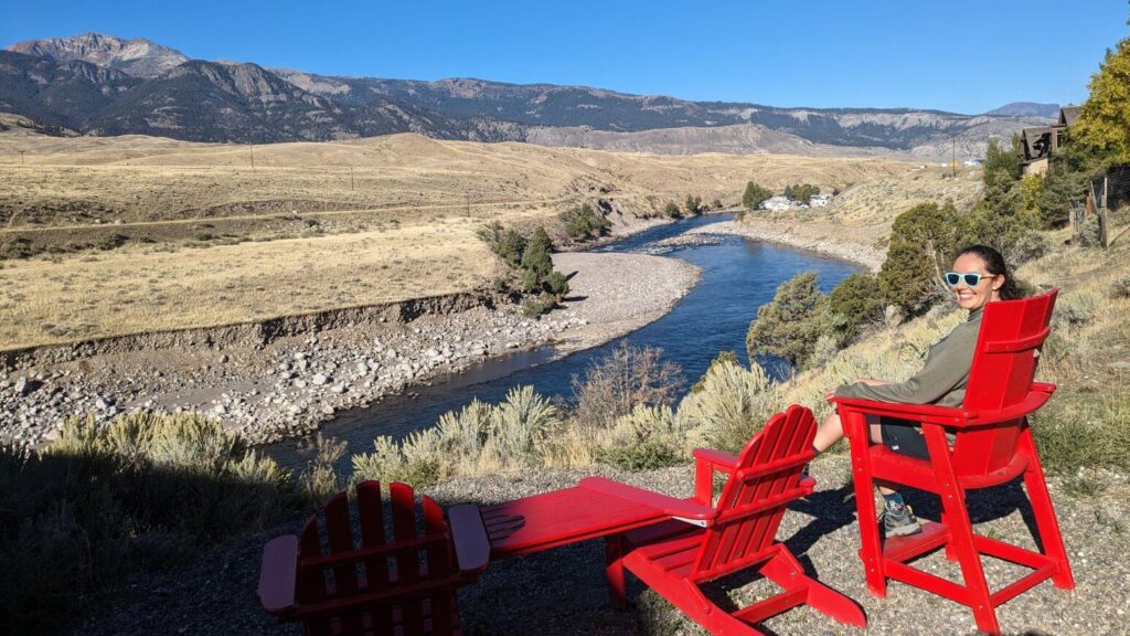 Sitting in a red adirondack chair along the Yellowstone River at the Ridgeline Hotel